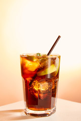 cocktail cuba libre in glass with straw on beige background