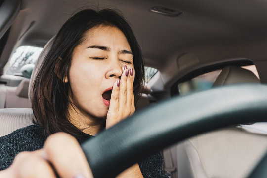 tired sleepy Asian woman yawning while driving the car 