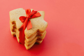 Stack of shortbread cookies in the shape of Christmas tree tied with red ribbon.