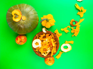 Dried fruits and vegetables slices apple, pumpkin in brown wicker basket on green background. Selective focus.