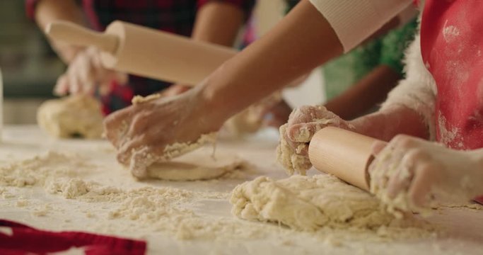 Handheld view of family rolling the dough for Christmas cookies 