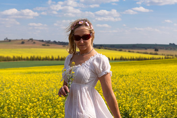 Female  by a field of flowering canola and rolling hills