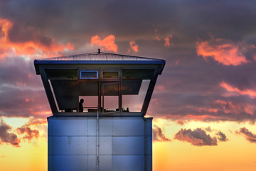 An air traffic control tower with the silhouette of an unidentifiable male traffic controller...
