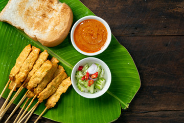 Pork satay - Grilled pork served with peanut sauce or sweet and sour sauce on Banana leaf - Asian food style on wood table