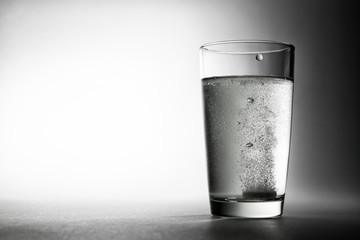 The effervescent tablet fell into a glass of water and dissolves.