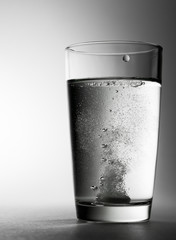 The effervescent tablet fell into a glass of water and dissolves.