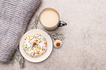 Hot coffee with a donut. Winter drink for a good mood with sweater, leaves and flowers. Old wood...