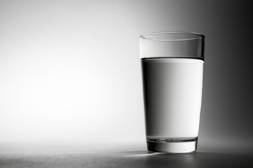 A glass with cheats of fresh water on a neutral background.