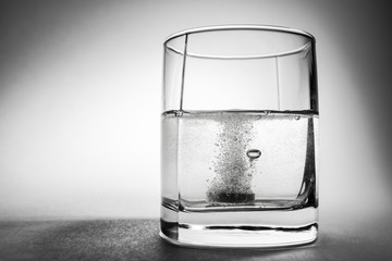 Effervescent aspirin tablet dropping to glass of water