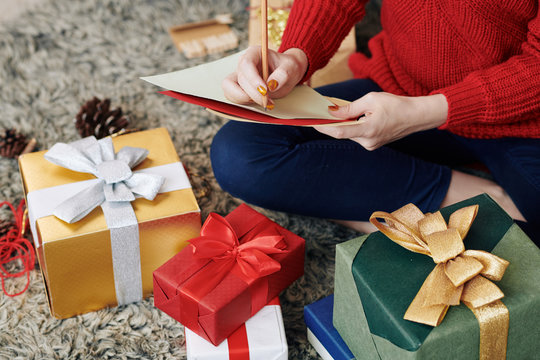 Cropped image of young woman writing list of presents for her family members