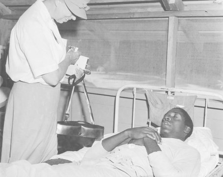 First Lady Eleanor Roosevelt visits a African American soldier in a South Pacific military hospital