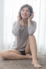 A sexy woman listening to music in the bedroom headphones with soft light by the window