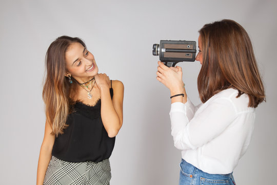 Dos chicas jugando con una c&aacute;mara de cine antigua de pel&iacute;cula de 8 mm; chicas haciendo de artistas de actriz y de directora de cine.