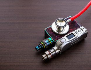 Conceptual image of uncertainty of health safety of e-cigarettes. Isolated close-up red stethoscope...