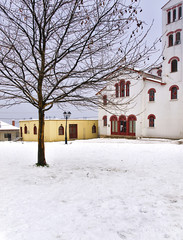 Bare tree snow covered village square and orthodox church in Elatohori,  Pieria, Greece.