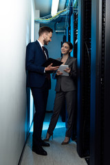 cheerful businesswoman and businessman with clipboard in data center