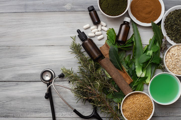 some plants, bulbs and medicinal seeds, with a rustic wooden background, and some pills and droppers next to a stethoscope