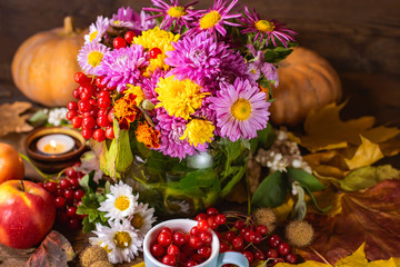 multi-colored autumn chrysanthemums and a cup of tea with mountain ash.