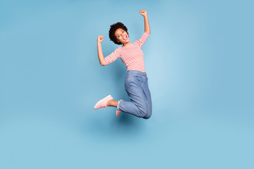 Full body photo of excited enthusiastic afro american girl jump show her triceps wear striped shirt...