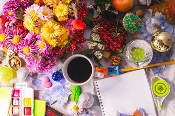 Notebook and stationery, paint pencils on a winter and autumn background. Watercolor maple leaves painted.