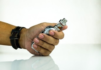Conceptual of recent uncertainty of health safety of e-cigarette. Isolated close-up hand holding vaping kit over reflective white. Text on colorful labels. Focus on labels.