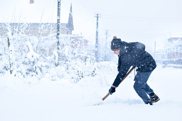  Teenager removing snow with a shovel in the winter