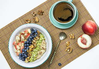 oatmeal breakfast with blueberries and peach and a cup of coffee