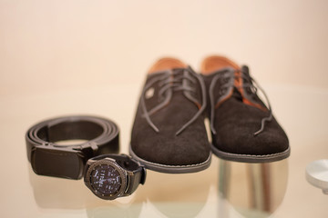 men's shoes belt watch accessories black on a glass table. groom's morning