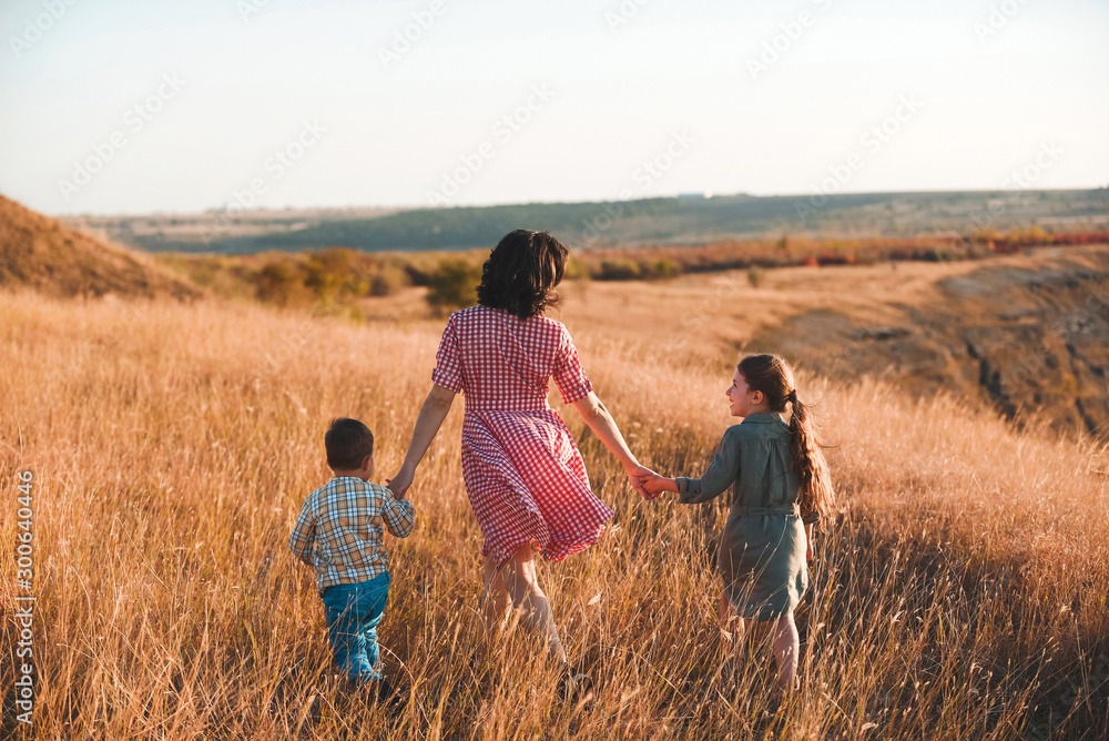 Poster mother walking with children in grass