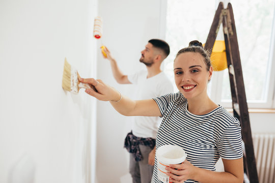 young couple decorating and painting indoor walls in their home