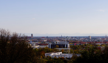 Munich skyline photographed from the Olympia hill in Munich Olympiapark on a clear day with the Alps on the background
