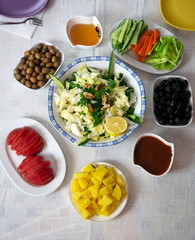 Breakfast plates lined up round on white tablecloth. Middle lettuce salad and lemon slice, boiled potatoes, honey, olives, cheese, sliced ​​tomato pepper carrot  https://cevirsozluk.com/