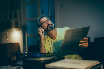 mid aged man relaxing in his home listening to a music
