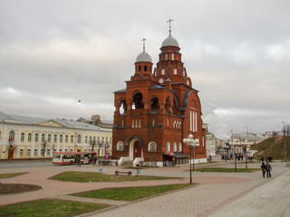 High red brick Church standing in the middle of the square against the gray sky