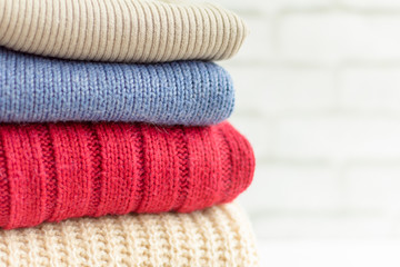 knitted fluffy sweaters are stacked on a light background