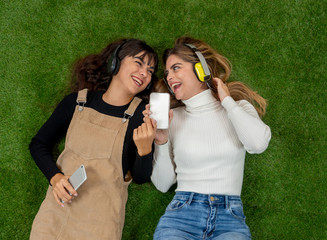 Pretty teenagers girl friends in headphones listening to music on their smart phones