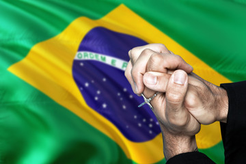 Brazil flag and praying patriot man with crossed hands. Holding cross, hoping and wishing.