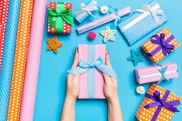 Top view of female hands holding a Christmas present on festive blue background. Holiday decorations and wrapping paper. New Year holiday concept