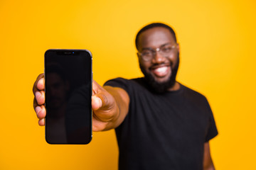 Portrait of positive afro american guy hold smartphone show modern technology gadget advertise...