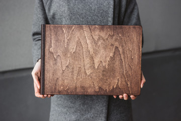 Girl holds wooden photo books. Woman holds a family photobook. Photo album wedding photoalbum with wooden leather cover.