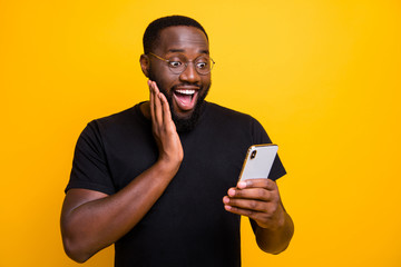Photo of ecstatic overjoyed man browsing through his telephone rejoicing in receiving positive...