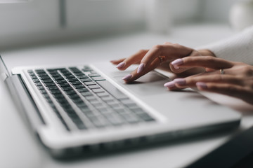 Woman hands are typing on the laptop keyboard, close-up. Closeup girl arms carefully writing on...