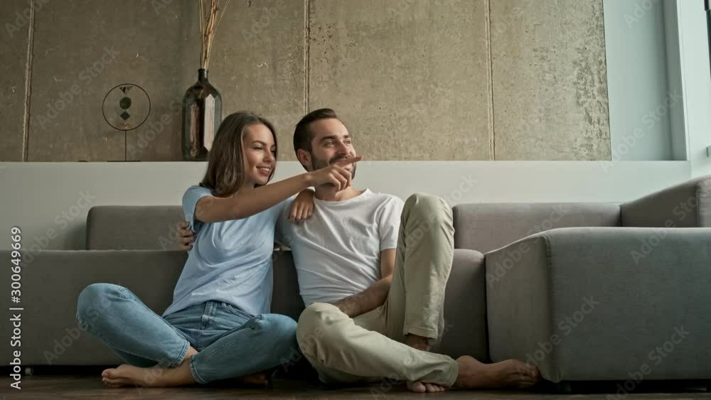 Sticker attractive cheerful young lovely couple hugging and looking to the side at the window while sitting 