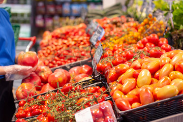 Female hand choosing tomatoes in the store. Concept of healthy food, bio, vegetarian, diet.