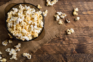 Air salty popcorn.A bowl of popcorn on a wooden table.Salt popcorn on the wooden background .  With space for text.Top view.popcorn texture.Chees . - obrazy, fototapety, plakaty