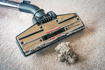 Closeup of vacuum cleaner head and dust on the floor. Cleaning, allergic and household concept.