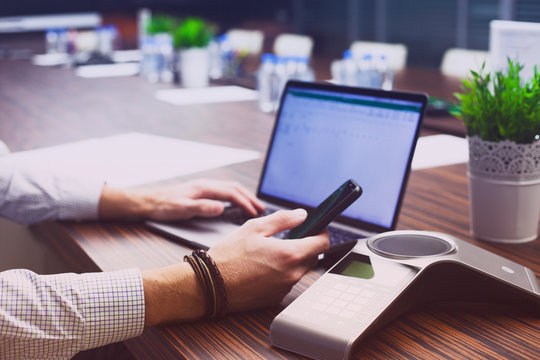 Male hand,  IP phone and laptop on the office table. Ip telephony and video meetings for business concept. Close up.