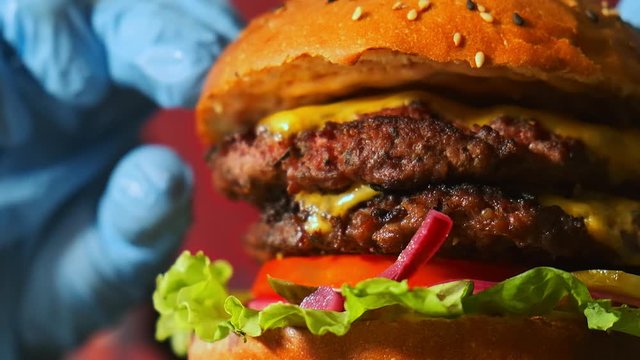Extra close-up of a chef cook preparing a double hamburger. Slow motion he puts a second bun and finishing assembling burger