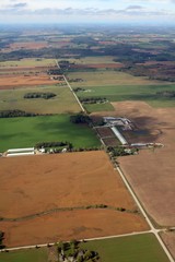 Fototapeta premium Arial view of farm fields on a sunny fall day near Hanover Ontario Canada with wind turbines off in the distance