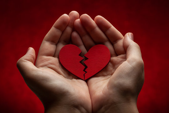 Woman holds broken heart in her hands. Crack in the red heart, Breaking the relationship